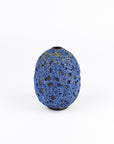 A small, rounded ceramic vase with a textured blue and black speckled pattern, centered on a clean white background.