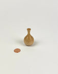 Small wooden vase next to a penny on a white background