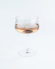 Wine glass with a small amount of rose wine on a white background