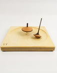 Wooden spinning plate with two tops against a white background