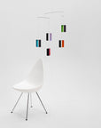 White chair with a colorful hanging mobile on a white background