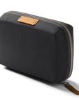 Black zippered pouch with brown leather patch on a white background