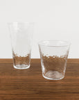 Two clear glass tumblers on a wooden surface with a white background