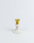 Decorative candle holder with gold top and white base on a light gray background