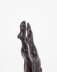 Detail of bronze sculpture of legs and feet on a white background