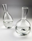 Two clear glass decanters on a gray background