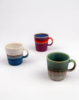 Three ceramic mugs with gradient colors on a white background