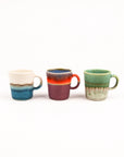 Three ceramic espresso cups with gradient colors on a white background