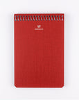 Red notebook with spiral binding on a white background