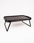 A black rectangular folding table with a textured top surface and slim angled metal legs, shown on a clean white background.