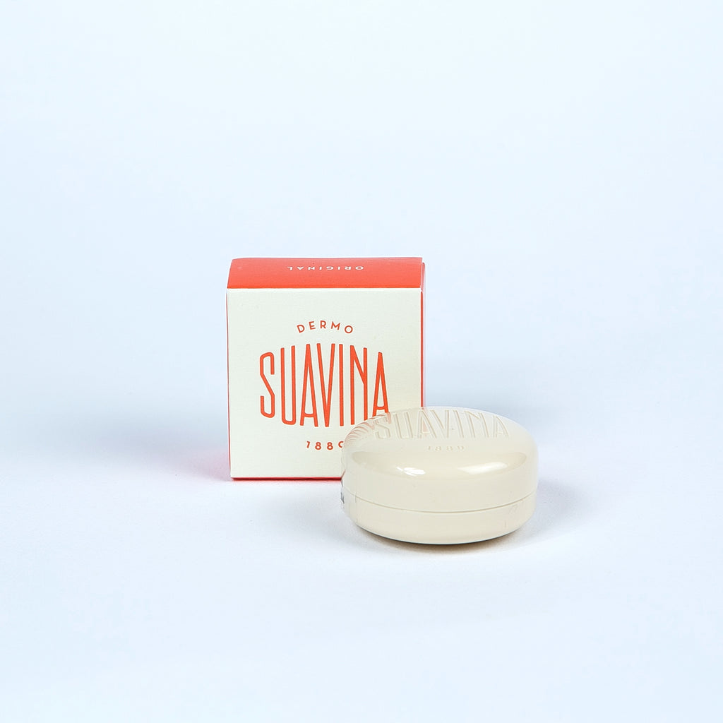 A small jar of Suavina lip balm next to its packaging box, with the brand name 'SUAVINA' displayed prominently on both the box and the jar.
