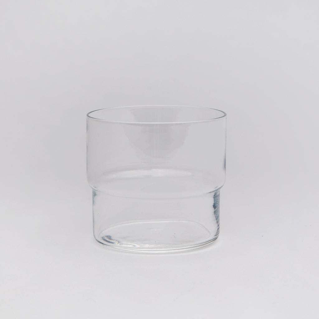 A clear stacking tumbler glass on a white background.