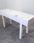 A small scaled handcrafted bench with a wooden seat and legs, displayed against a simple background.