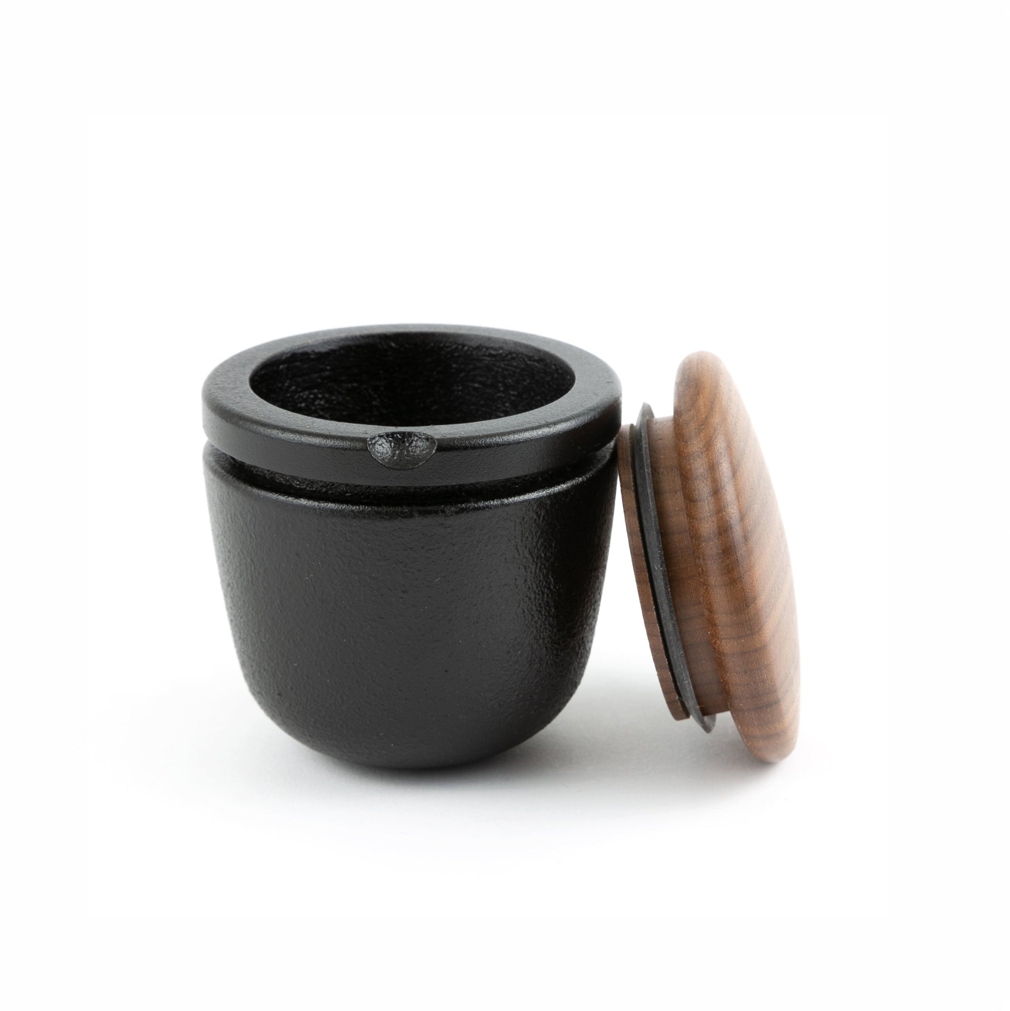 Black iron grinder container with a wooden lid on a white background