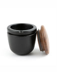 Black iron grinder container with a wooden lid on a white background