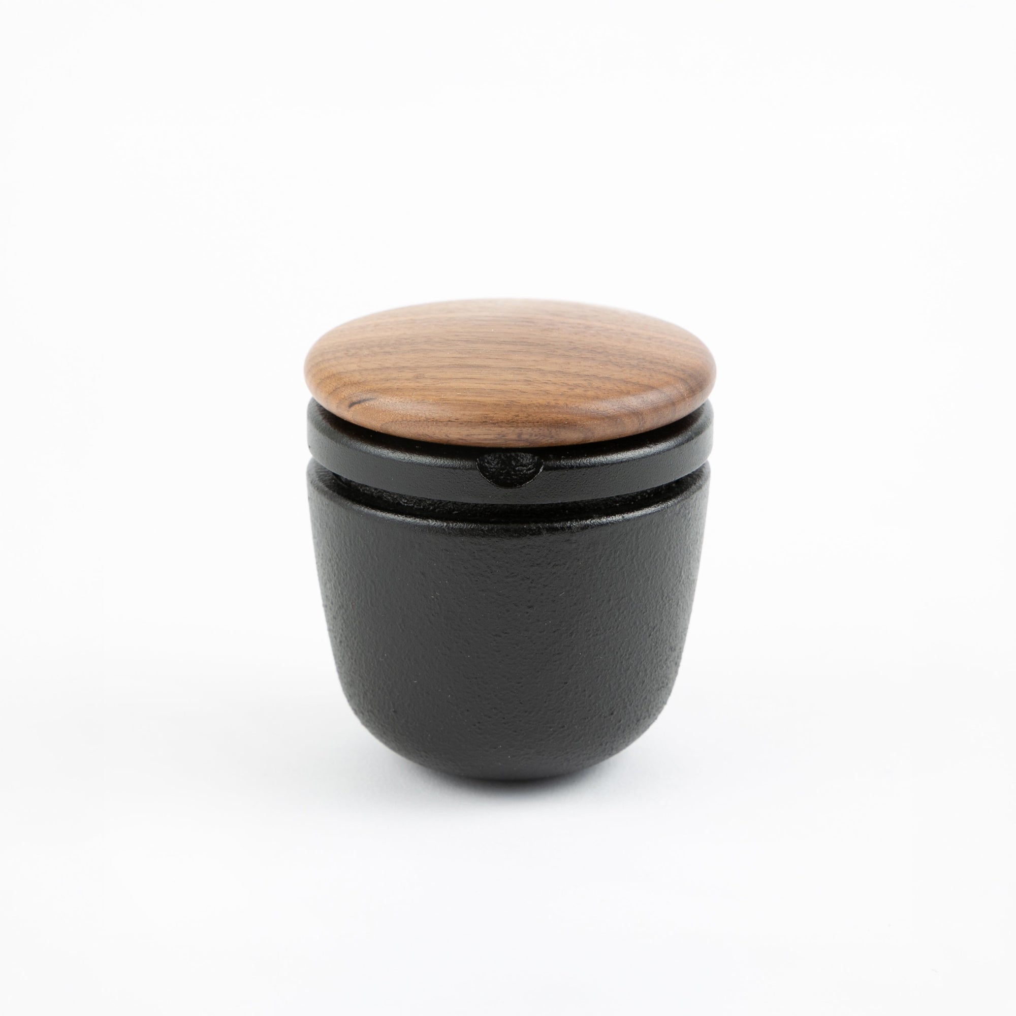 Black container with a wooden lid on a white background