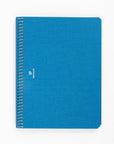 A blue A5 sized notebook with a stylized carrier pigeon logo on the cover, binding visible on the side.