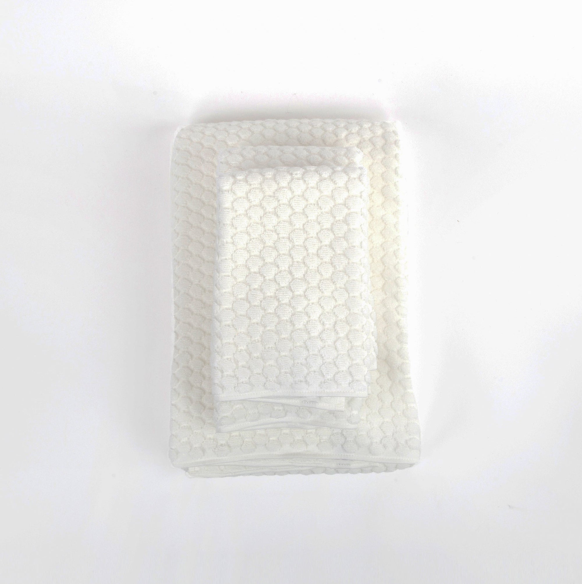 Stack of white towels with textured surface on a white background