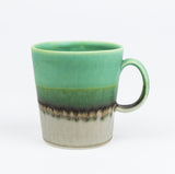 Green ceramic mug with a gradient design on a white background