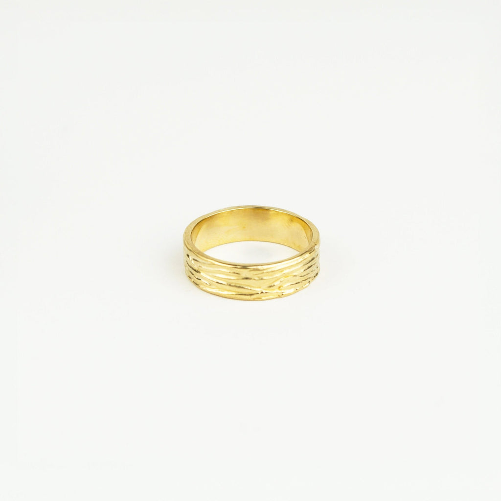 Gold ring with textured design on a white background
