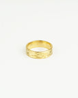 Gold ring with textured design on a white background