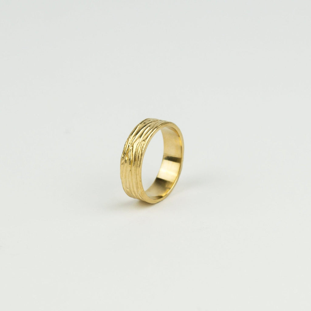 Gold ring with a textured design on a light gray background