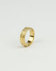 Gold ring with a textured design on a light gray background