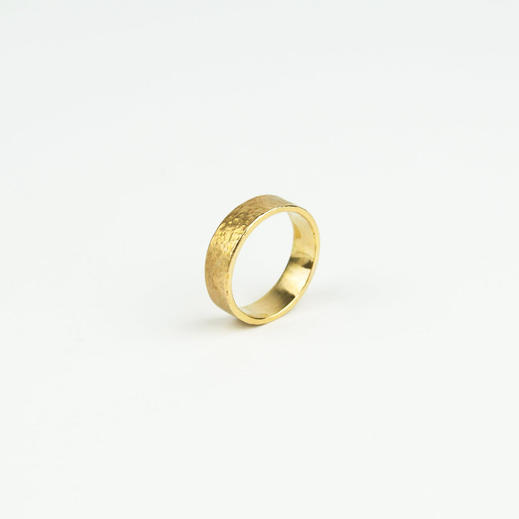 Gold ring with a textured surface on a white background