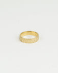 Gold ring with textured design on a light gray background