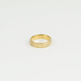 Gold ring with textured design on a light gray background