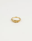 Gold ring with small beads on a light beige background