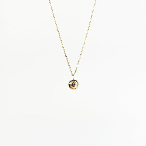 Gold necklace with a small round pendant on a white background
