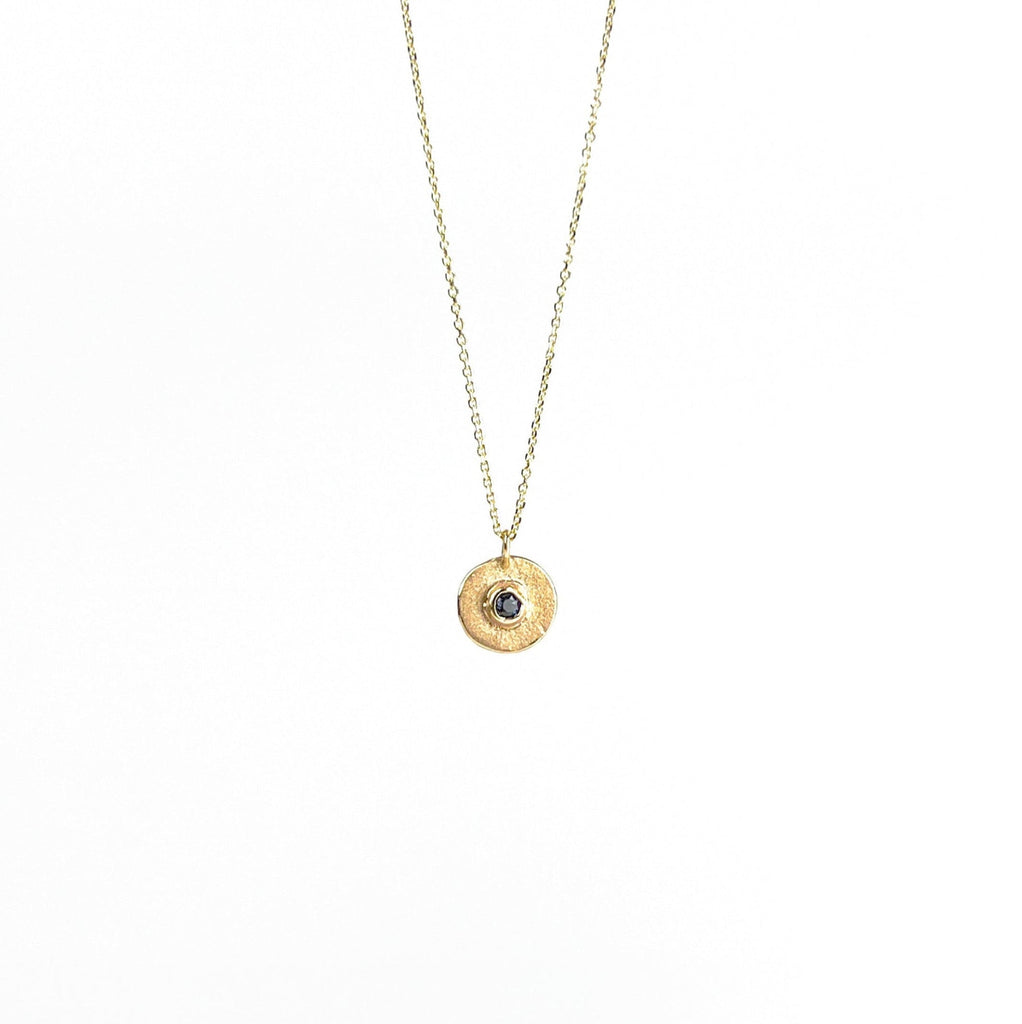 Gold necklace with a round pendant on a white background