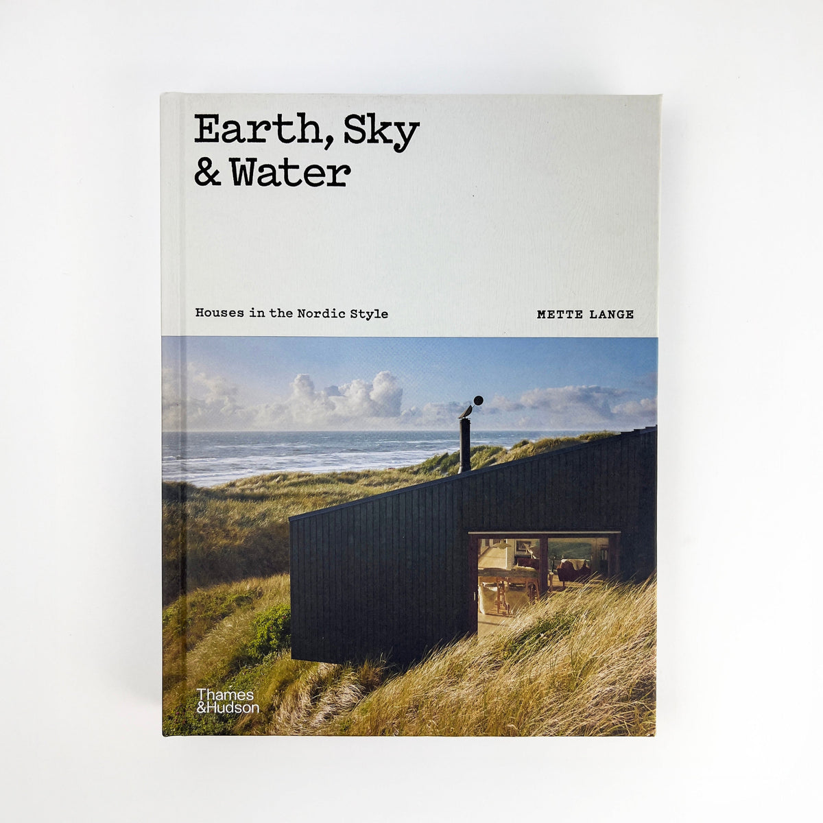 Book cover of 'Earth, Sky &amp; Water' with a house on a hill overlooking the ocean.