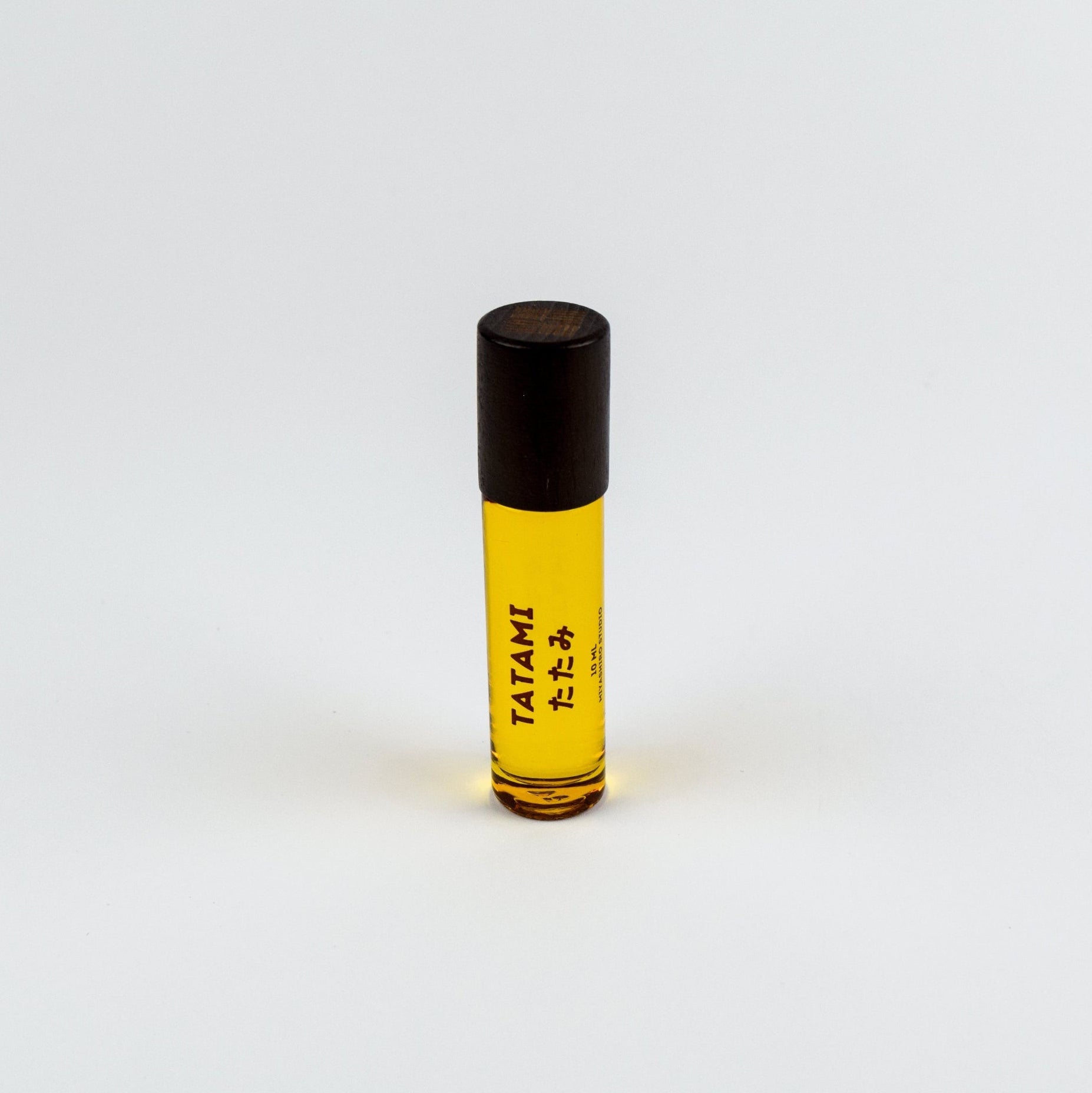 Small rollerball bottle with yellow liquid and black cap on a white background