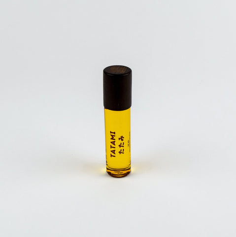 Small rollerball bottle with yellow liquid and black cap on a white background