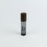 Small cylindrical container with brown top and black bottom on a white background