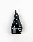 Black bottle with white polka dots and 'Comme des Garcons' branding on a white background