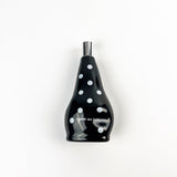 Black bottle with white polka dots and 'Comme des Garcons' branding on a white background