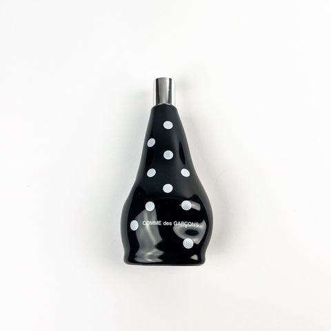 Black bottle with white polka dots and 'Comme des Garcons' branding on a white background