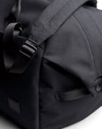Close-up of a black duffel bag with a visible brand logo on a white background