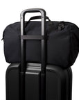 Black rolling suitcase with a black duffel bag on top