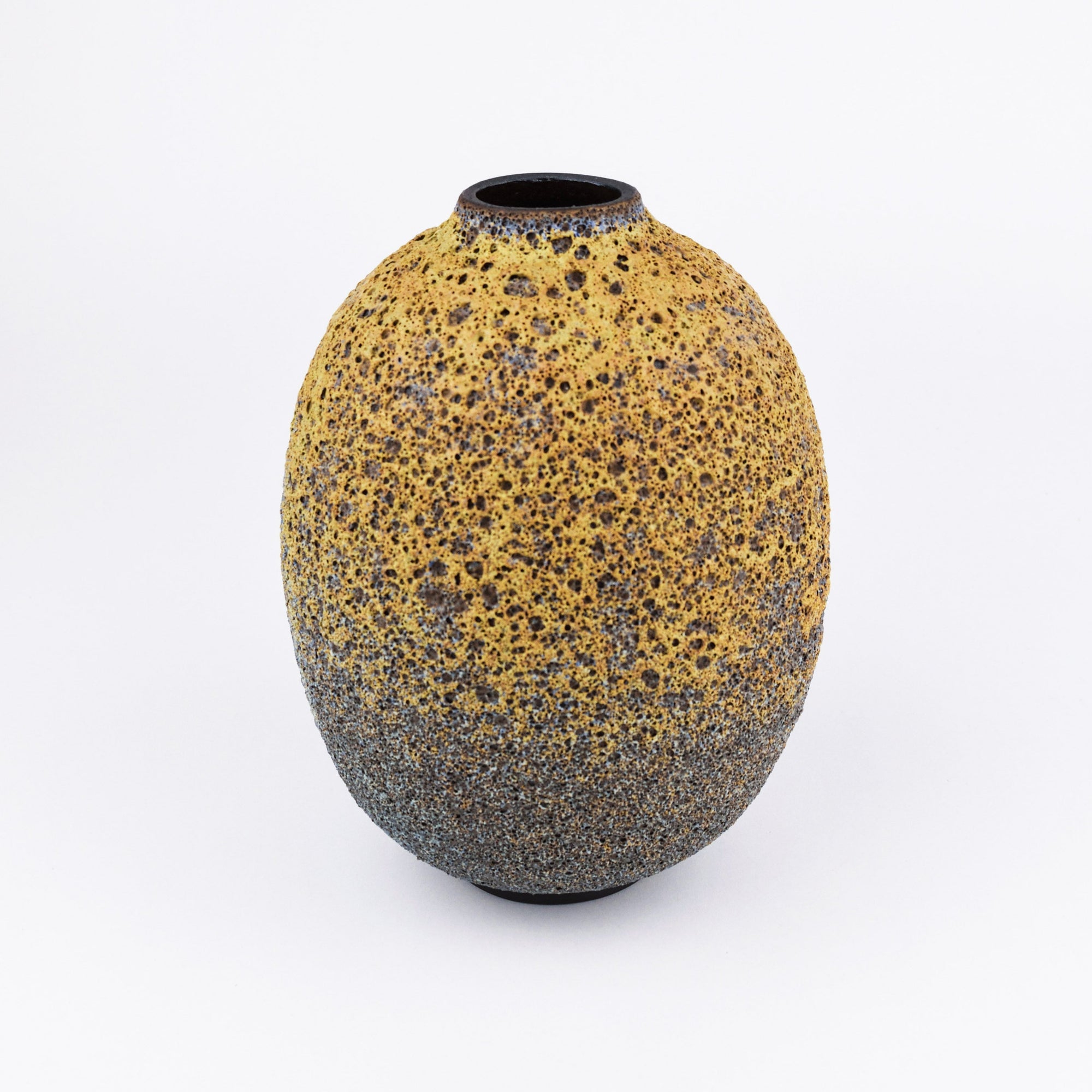 An oval-shaped ceramic vase with a textured, speckled glaze transitioning from a warm mustard yellow at the top to a dark charcoal gray blue at the bottom, set against a plain white background.