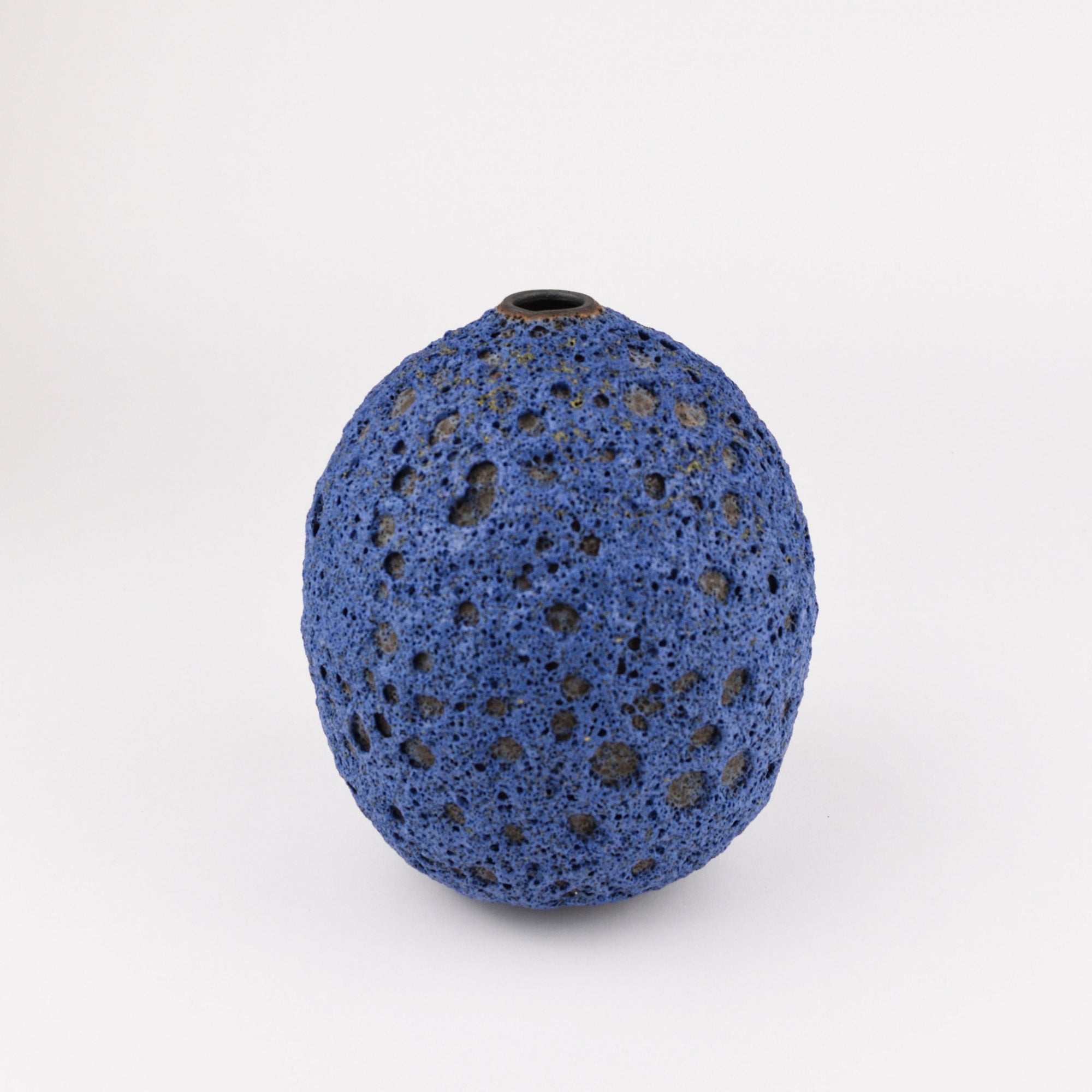 A small blue highly textured ceramic vase with a short neck, photographed on a clean white background.