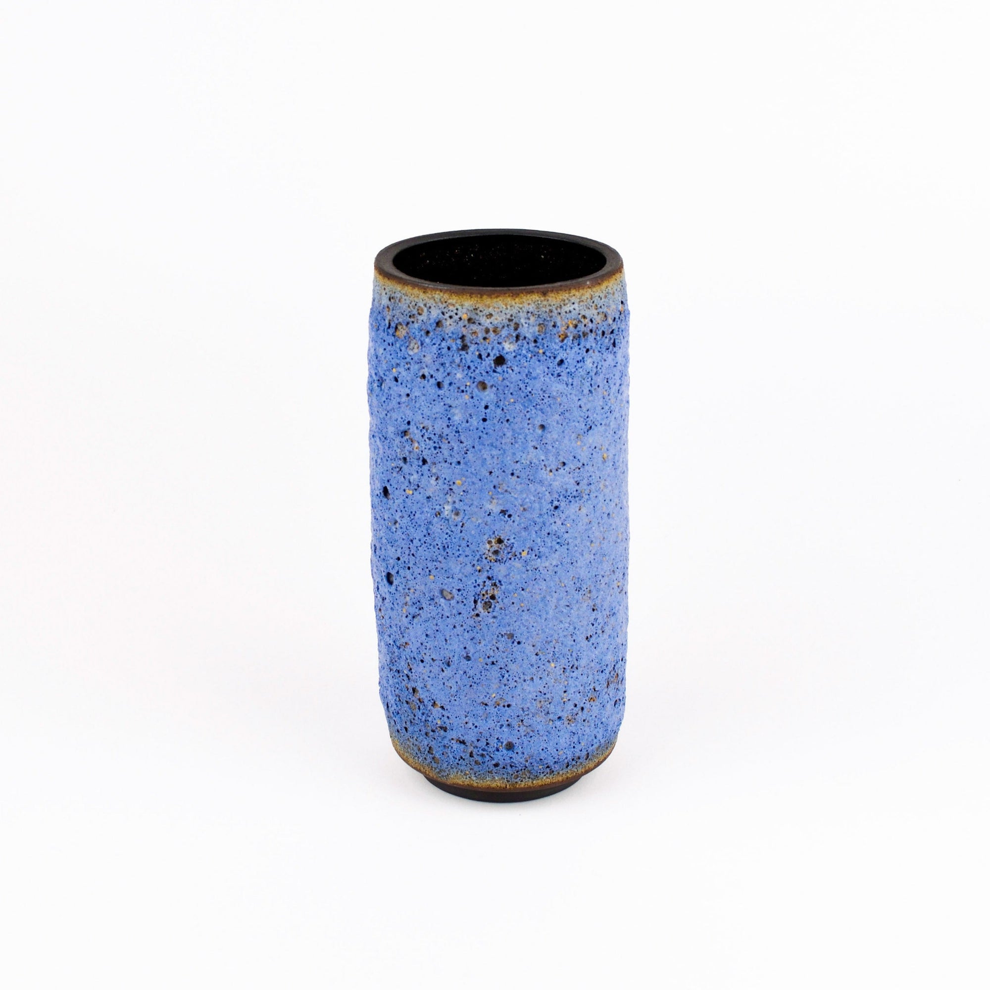 A small cylindrical ceramic vase with a textured blue glaze and a dark, unglazed black interior, set against a plain white background.