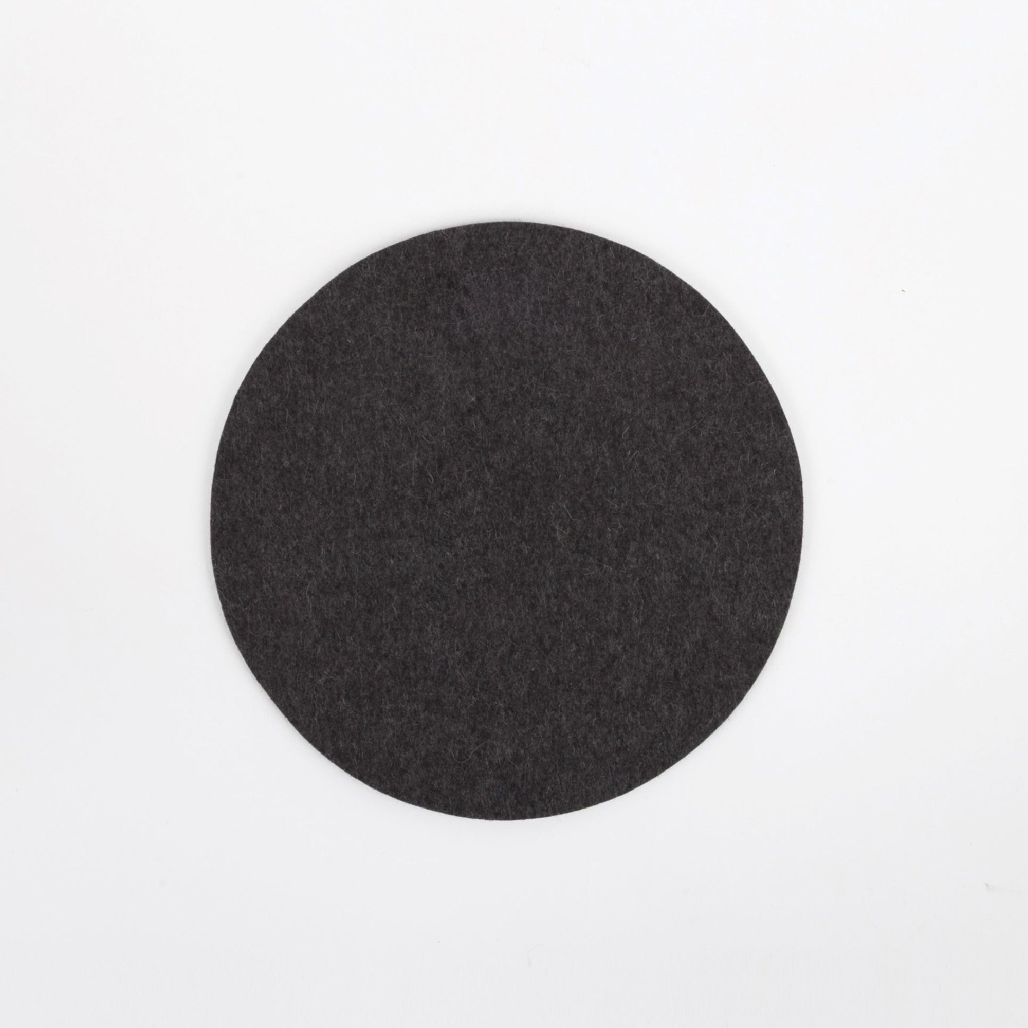 Round black felt coaster on a white background