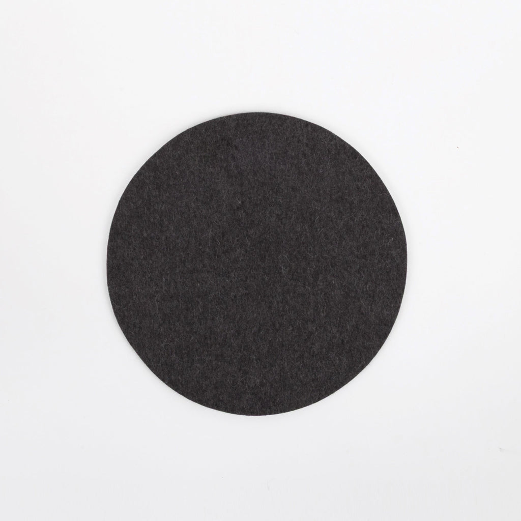 Round black felt coaster on a white background