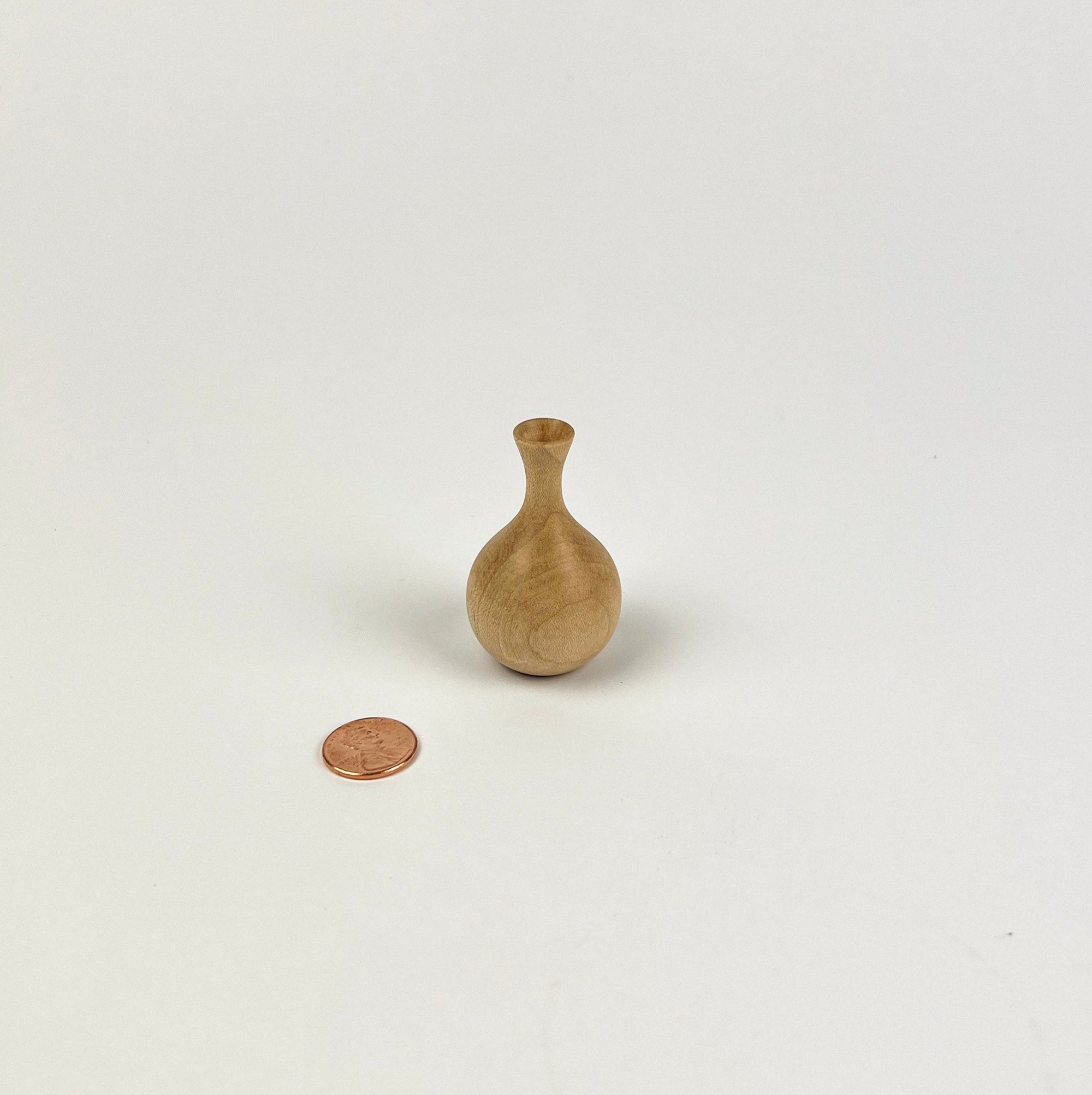 Small wooden vase next to a penny on a white background