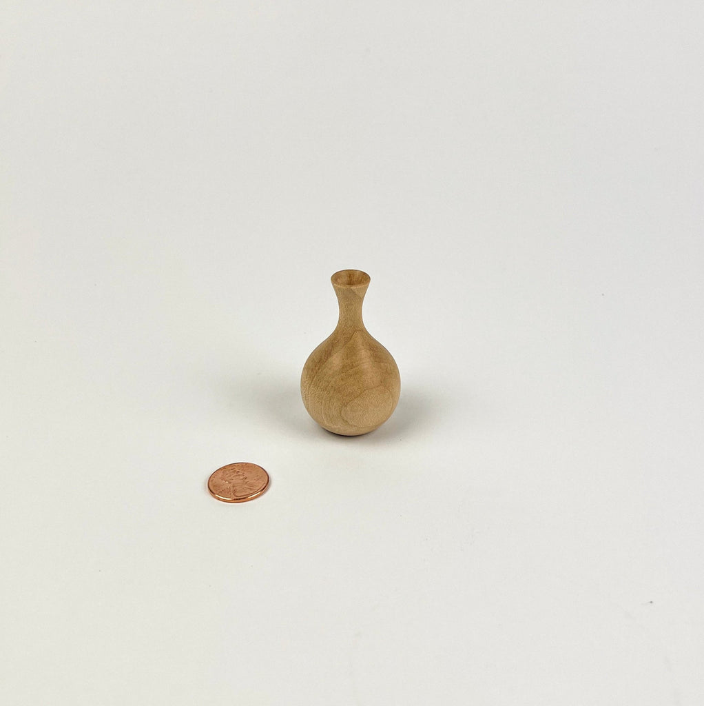 Small wooden vase next to a penny on a white background