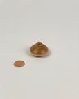 Small wooden vase next to a penny on a white background